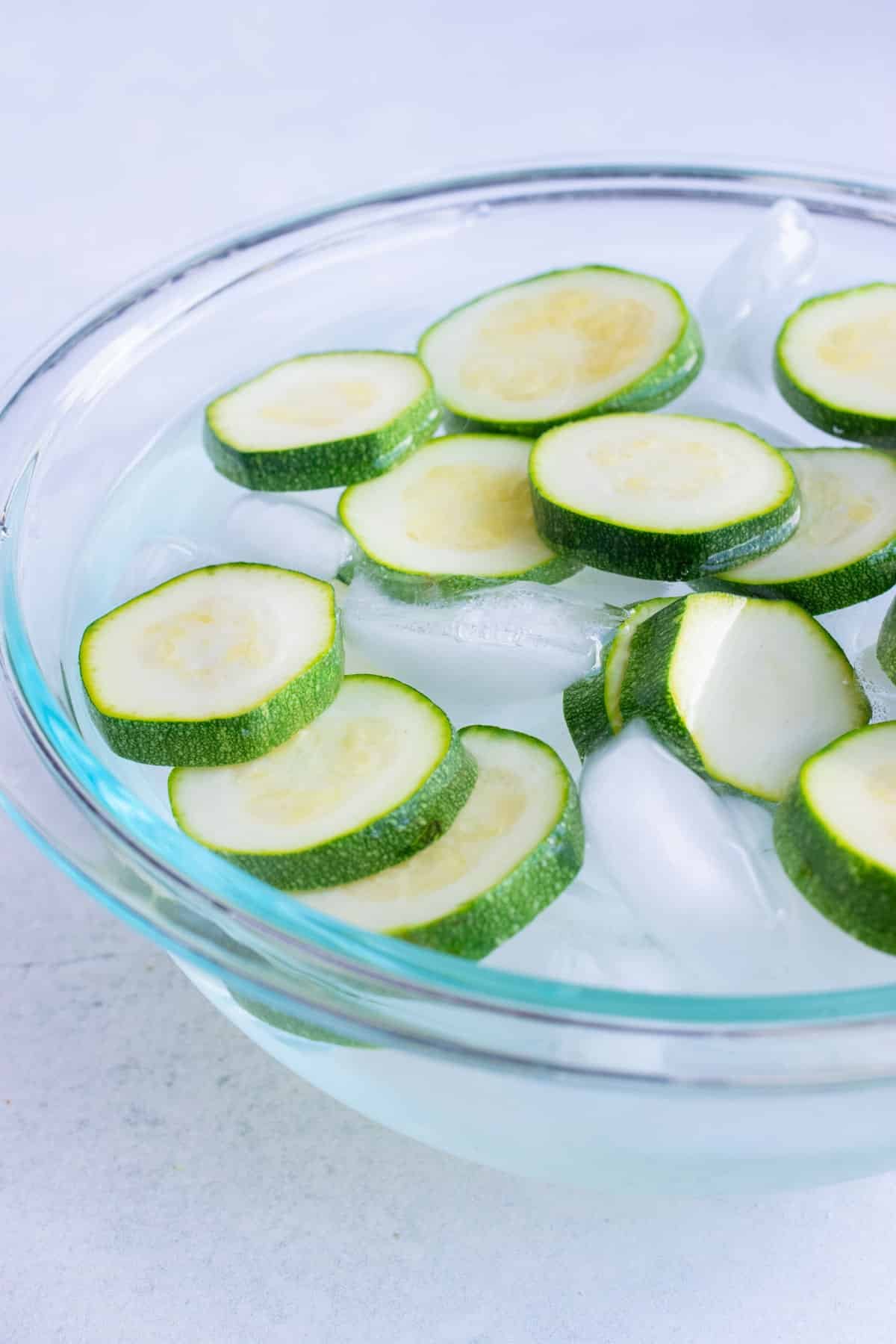 Instructional pictures for shocking summer squash by placing cooked zucchini immediately into an ice bath to halt cooking and then drying them off.