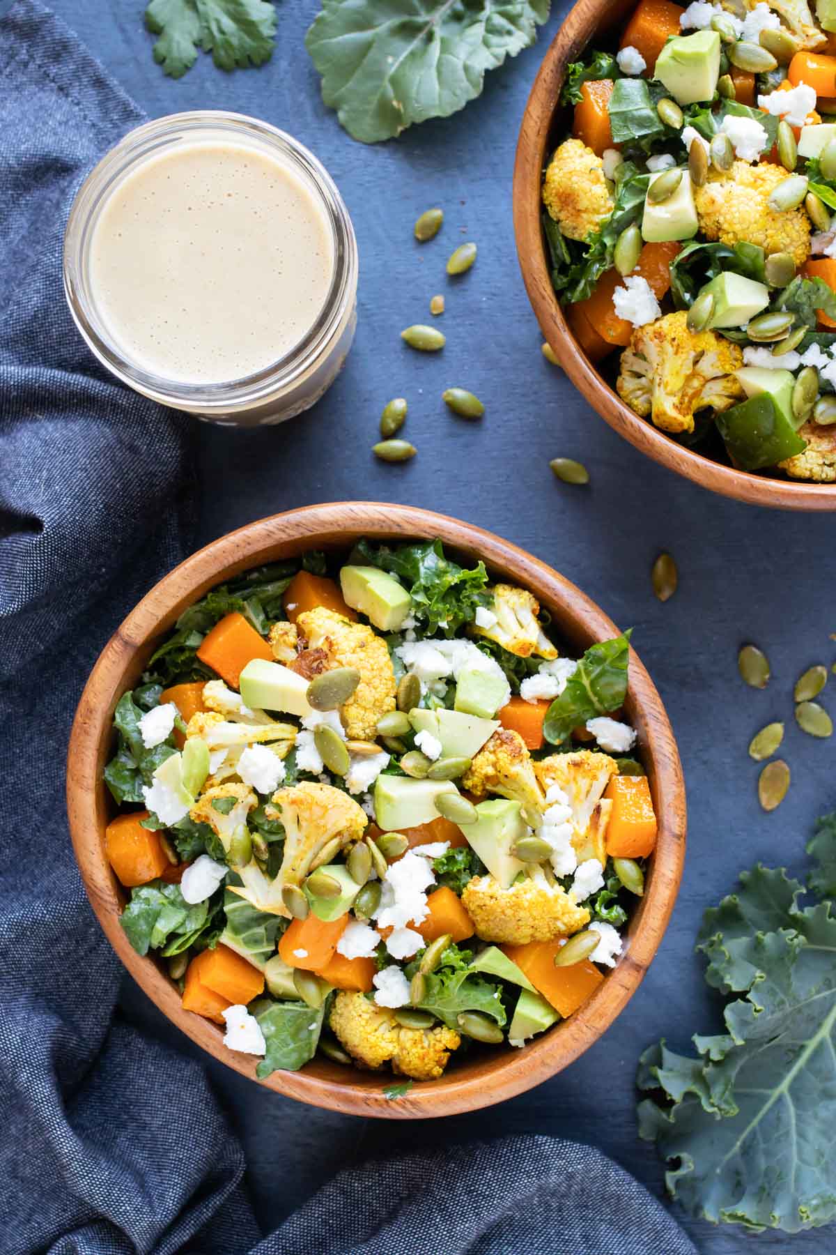 Two wooden bowls full of a healthy homemade roasted vegetable salad with cauliflower and butternut squash.