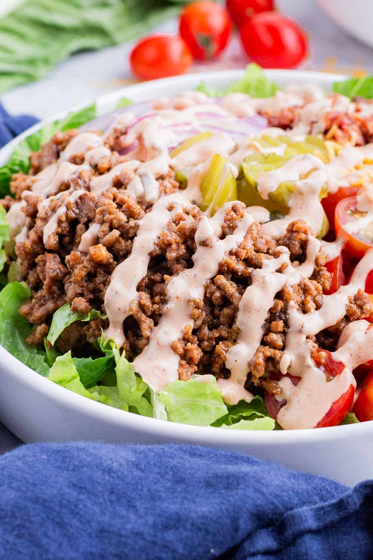 A burger bowl is topped with drizzled secret sauce.