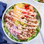 A fork digs into a big bowl full of deconstructed burger.