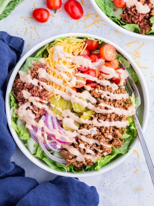 A fork digs into a big bowl full of deconstructed burger.