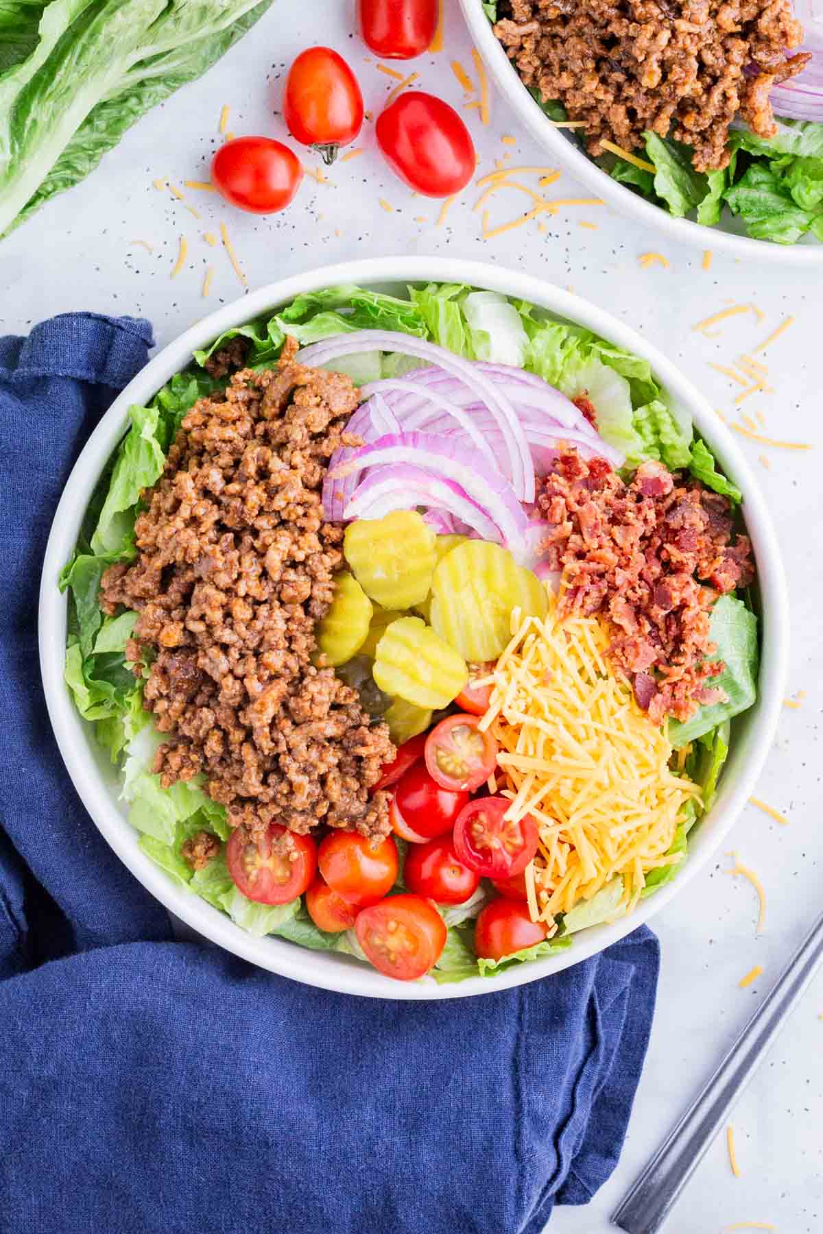 The burger bowl is built with lettuce, ground beef, and toppings.