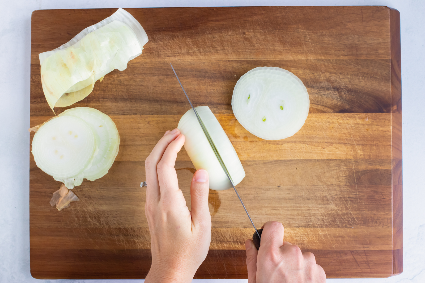 Slicing a peeled sweet onion into thick rounds for homemade onion rings.