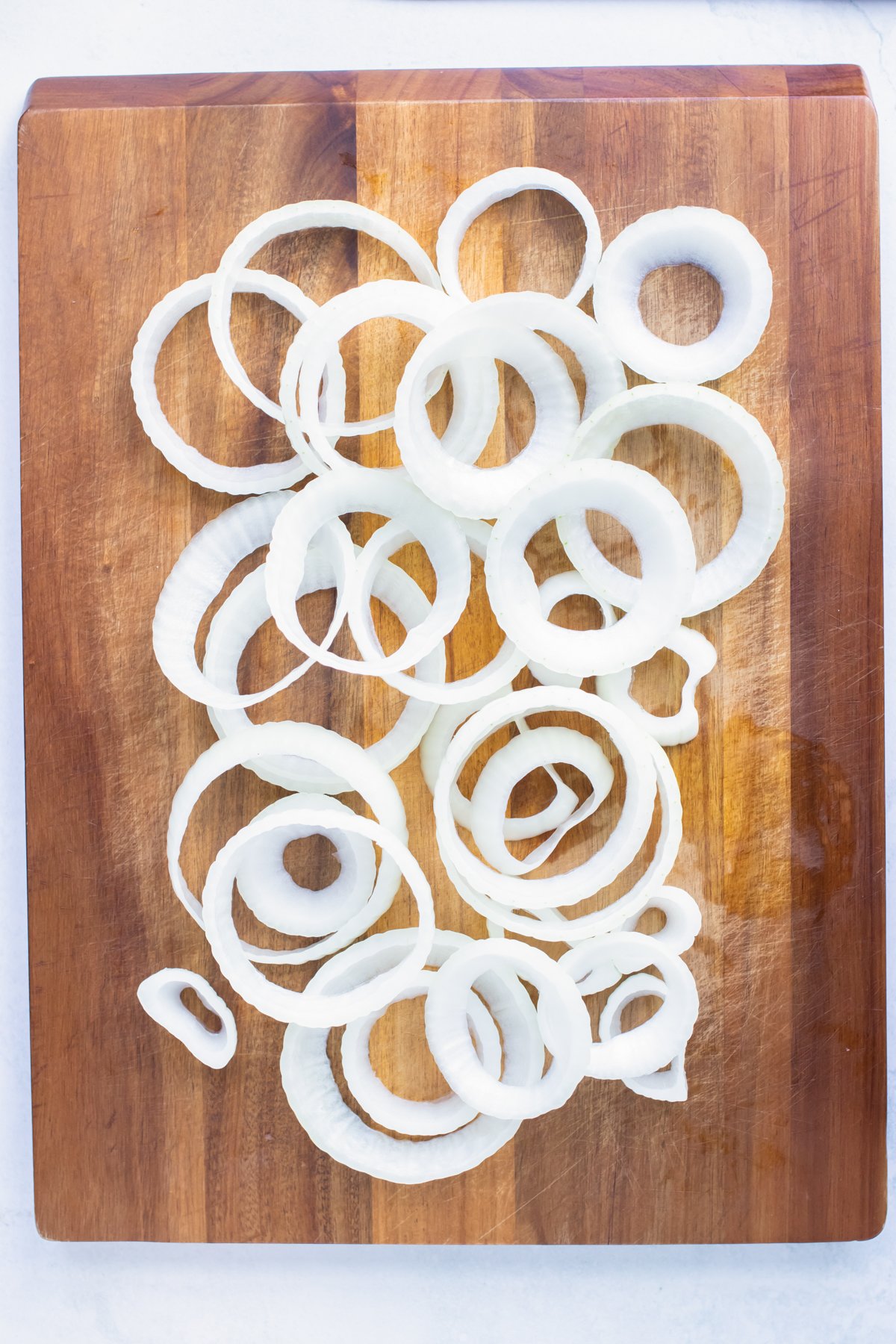 Sliced onions are separated into singular onion rings and prepped for breading.