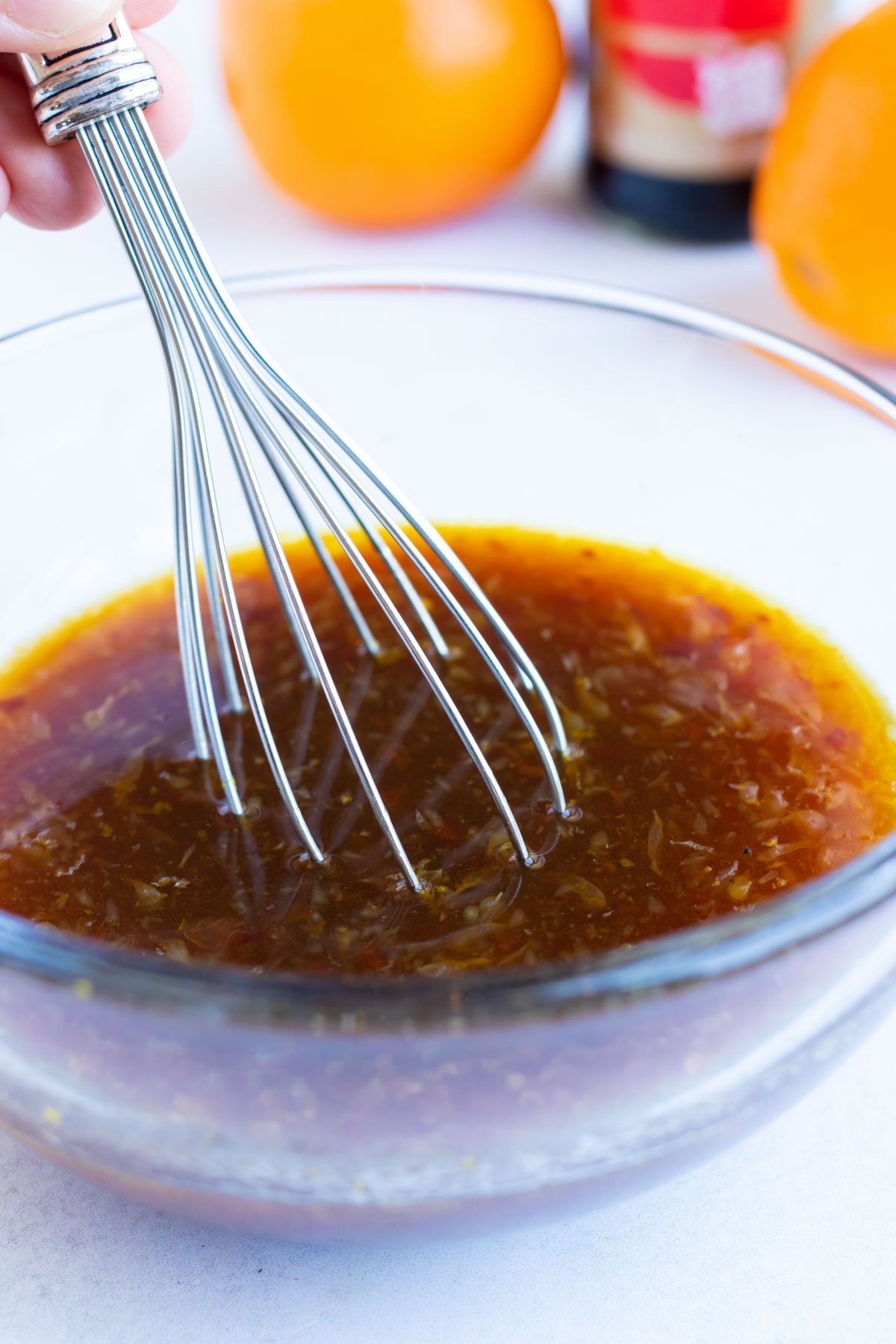 A healthy orange sauce being whisked together in a clear bowl.