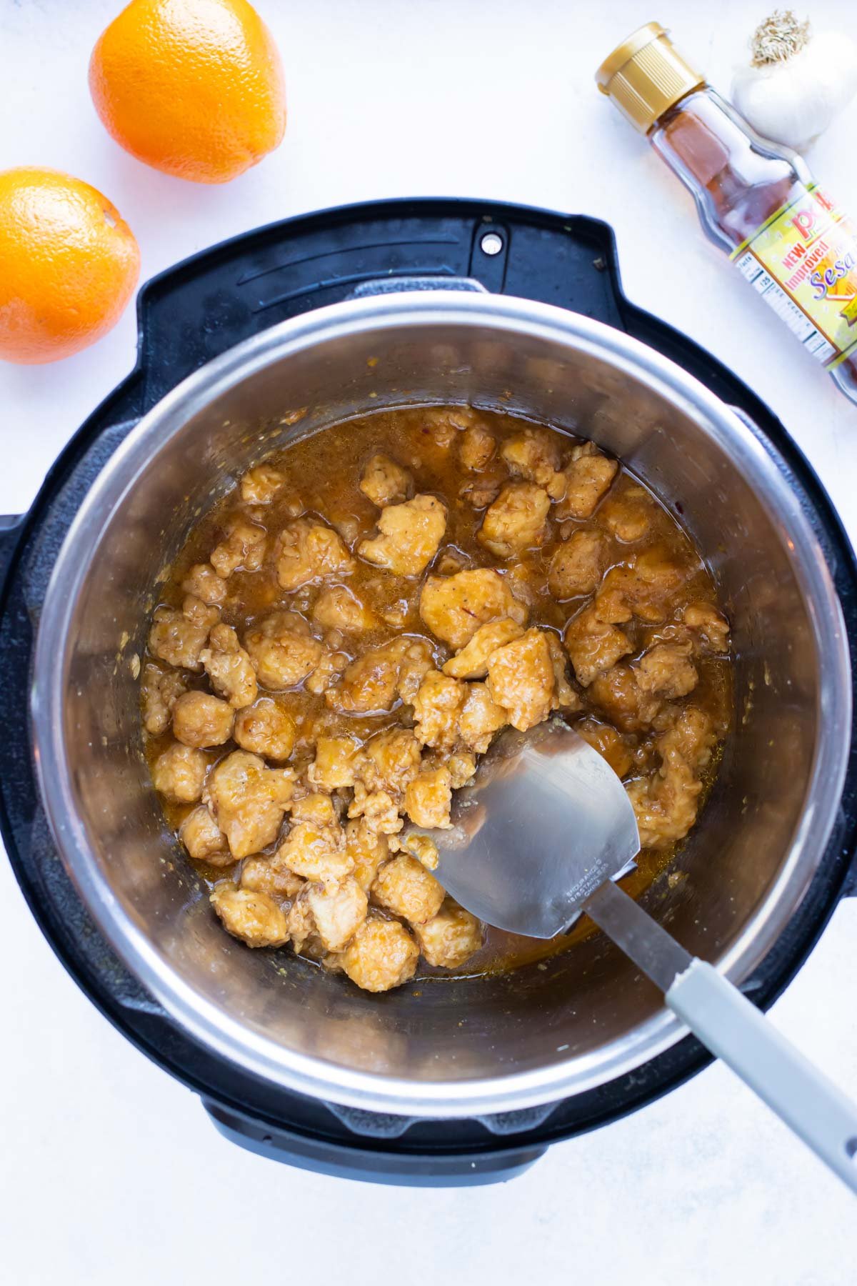 Chicken and sauces are stirred in an Instant Pot before cooking.