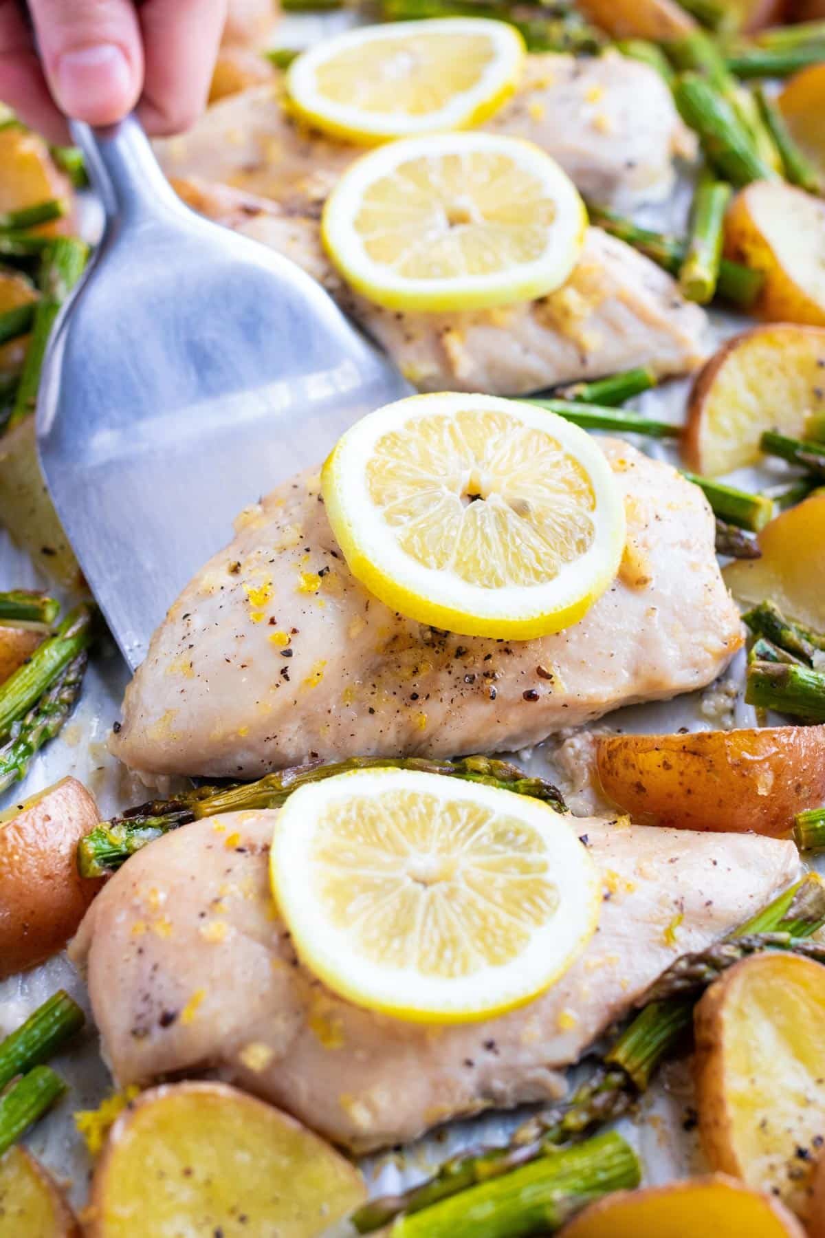 Sheet Pan Chicken and Asparagus RECIPE on a sheet pan with a spatula.