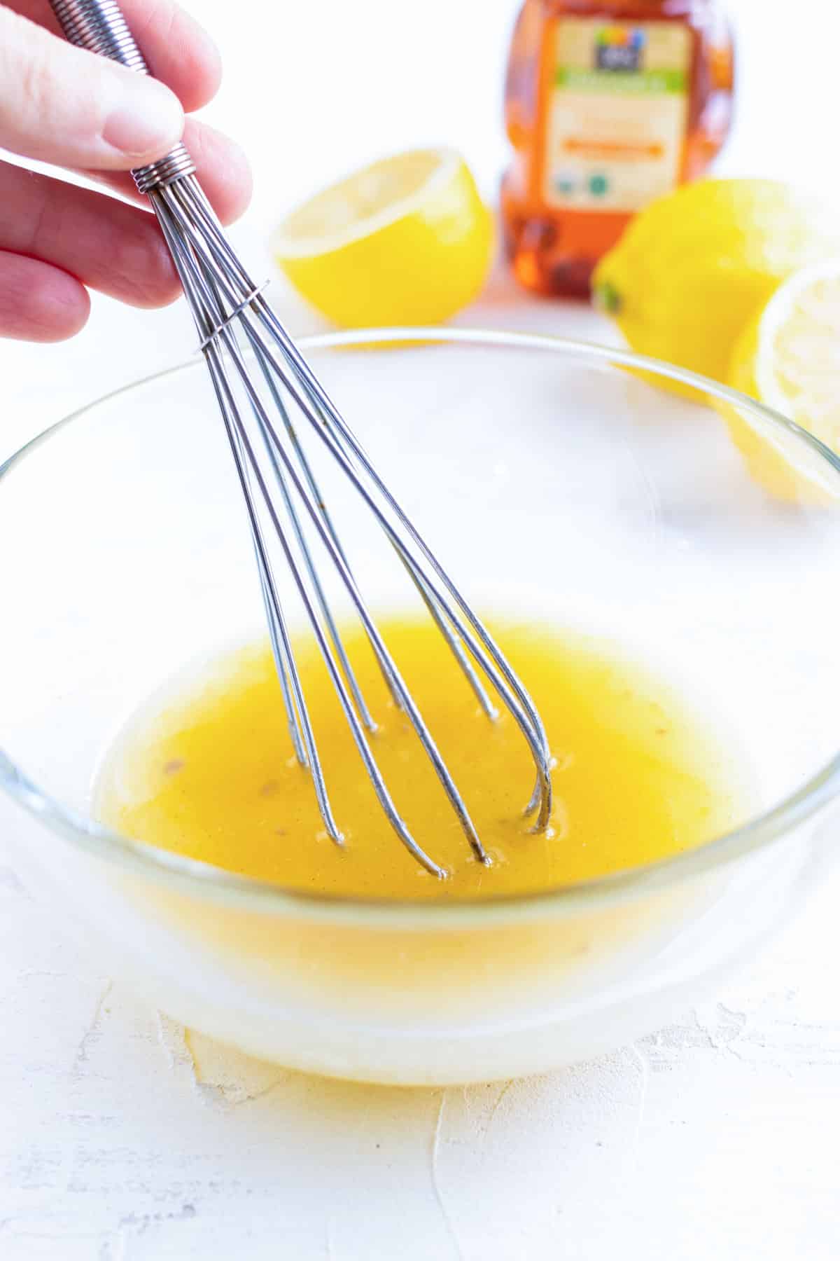 A lemon garlic butter sauce being whisked in a clear bowl for an oven baked chicken breast recipe.