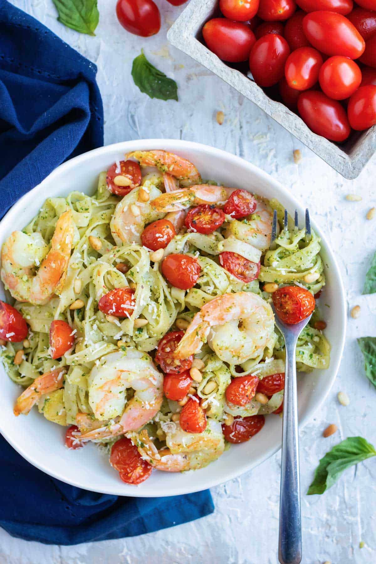 A healthy pesto pasta with shrimp, tomatoes, and pine nuts.