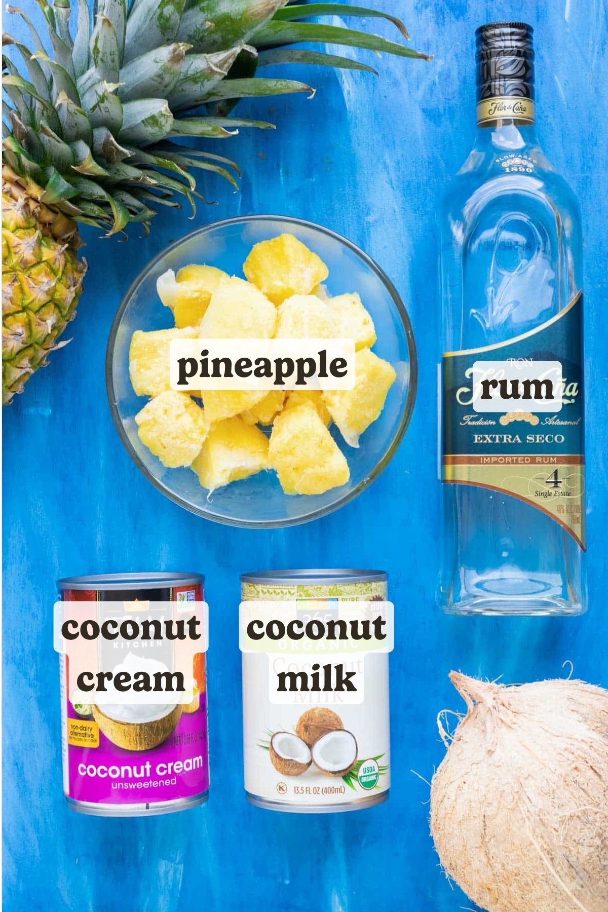 Fresh pineapple, coconut milk, coconut cream, and white rum as the ingredients in a pina colada recipe.