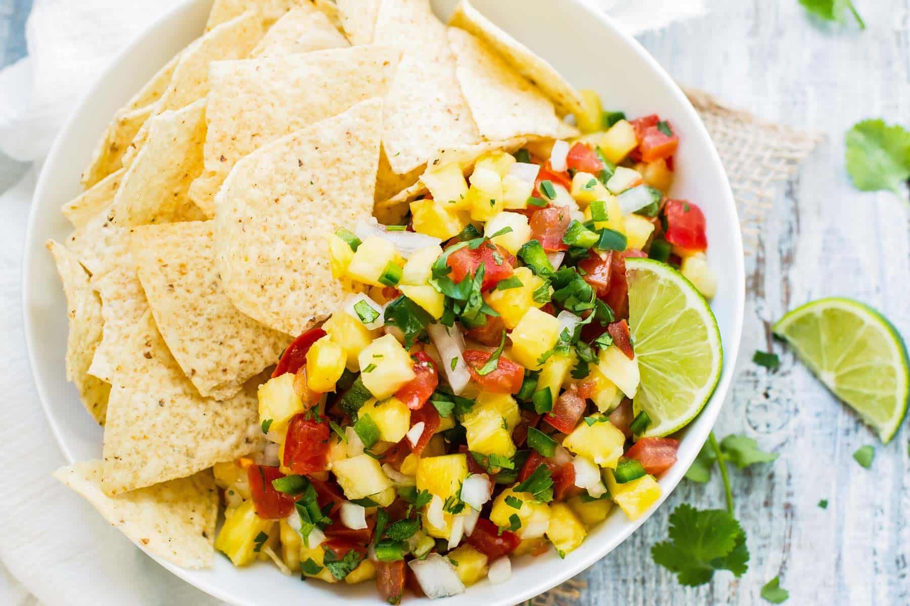 Pico de Gallo made with pineapples and lime in a bowl with tortilla chips.