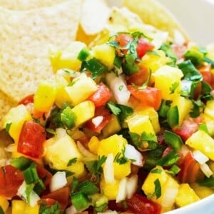 Gluten-free pineapple pico with tortilla chips and lime in a bowl ready for snacking.