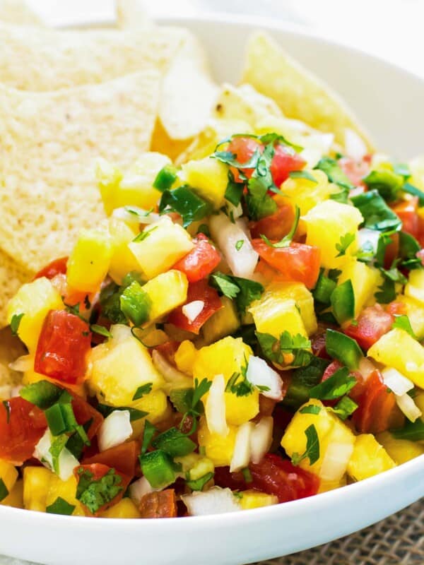 Gluten-free pineapple pico with tortilla chips and lime in a bowl ready for snacking.
