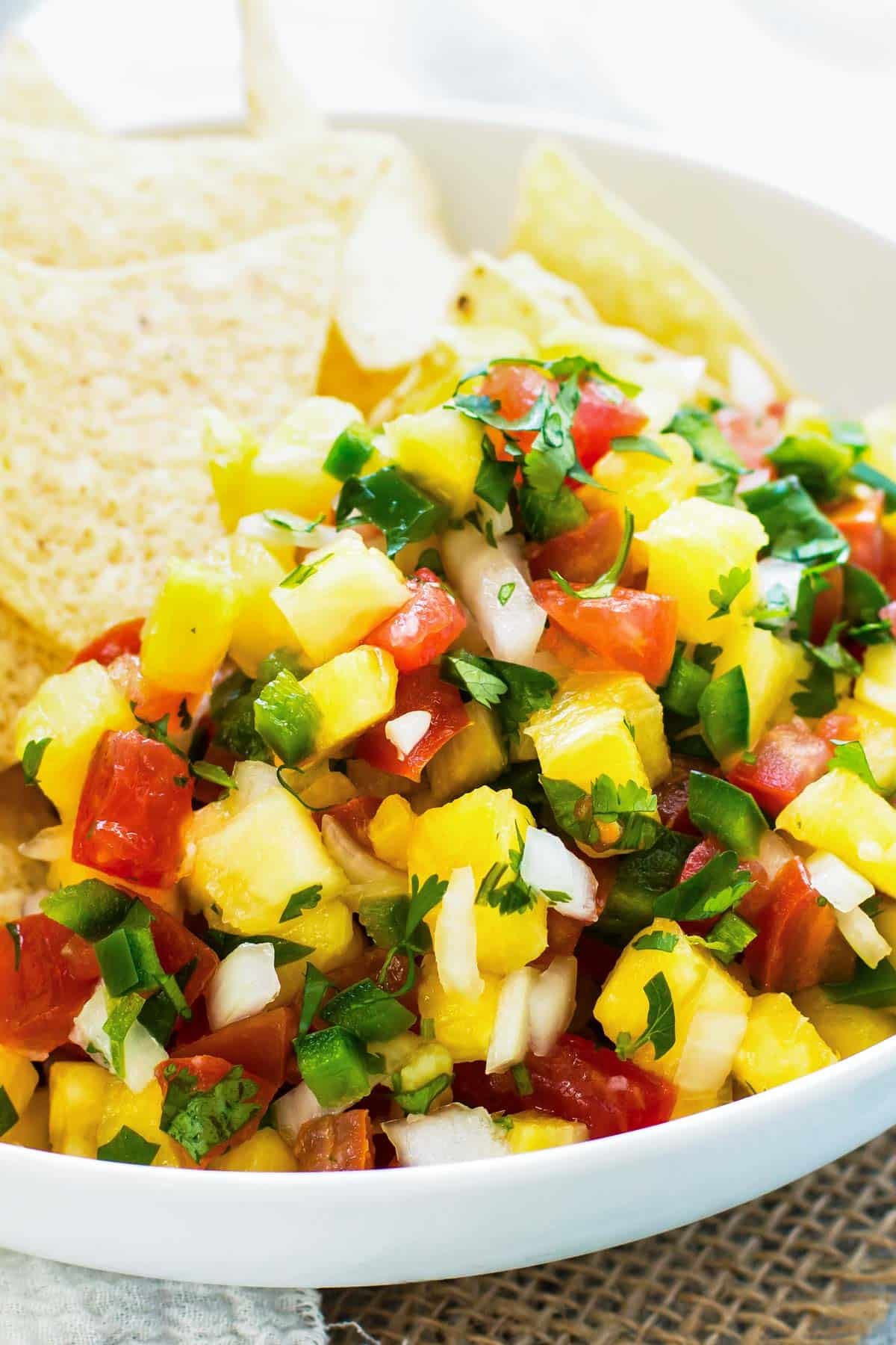 Gluten-free pineapple pico with tortilla chips and lime in a bowl ready for snacking.