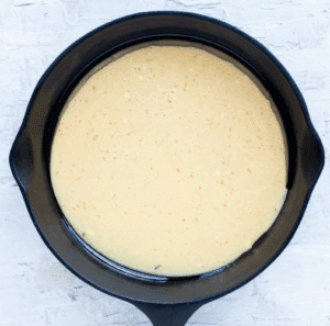 The pancake batter is poured into the hot cast iron skillet.