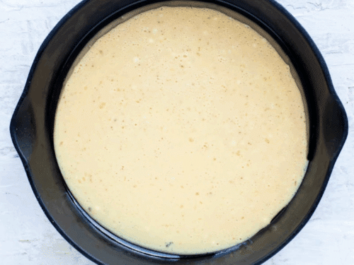 The pancake batter is poured into the hot cast iron skillet.