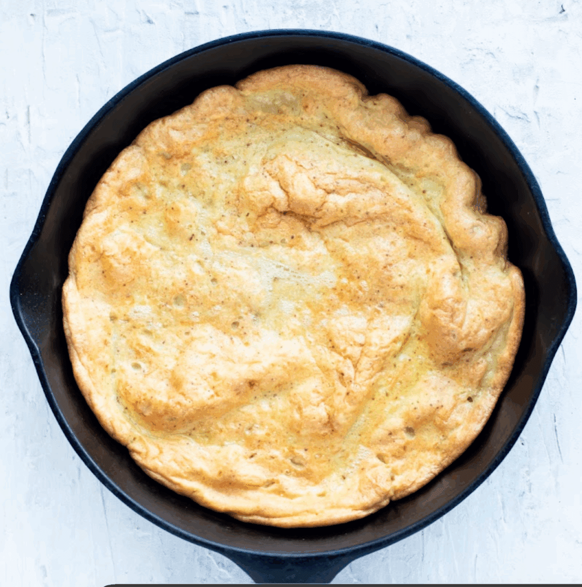 A Dutch baby pancake puffed up after baking in the oven in a cast-iron skillet.
