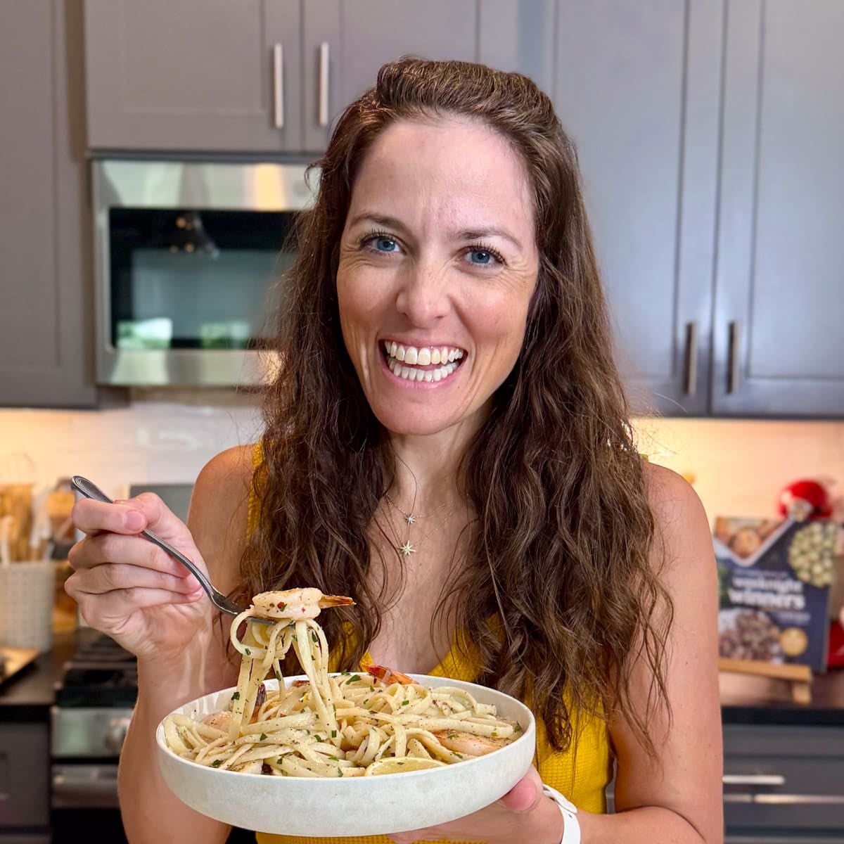 London Lea in her Austin, Texas kitchen picking up a bite of shrimp scampi linguine.