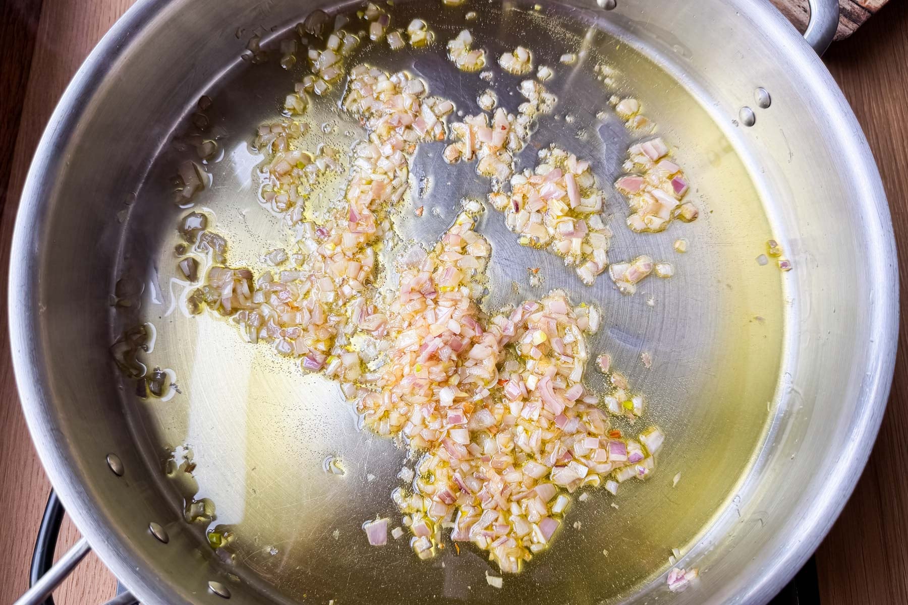 Garlic and shallots softening in olive oil in a skillet for shrimp scampi linguine