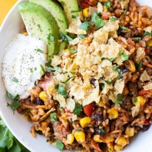 A Mexican beef and rice skillet recipe is served in a white bowl with tortilla chips and sour cream.