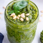 Basil leaves top a fresh basil pesto sauce to be used with bruschetta, pasta, or chicken recipes.