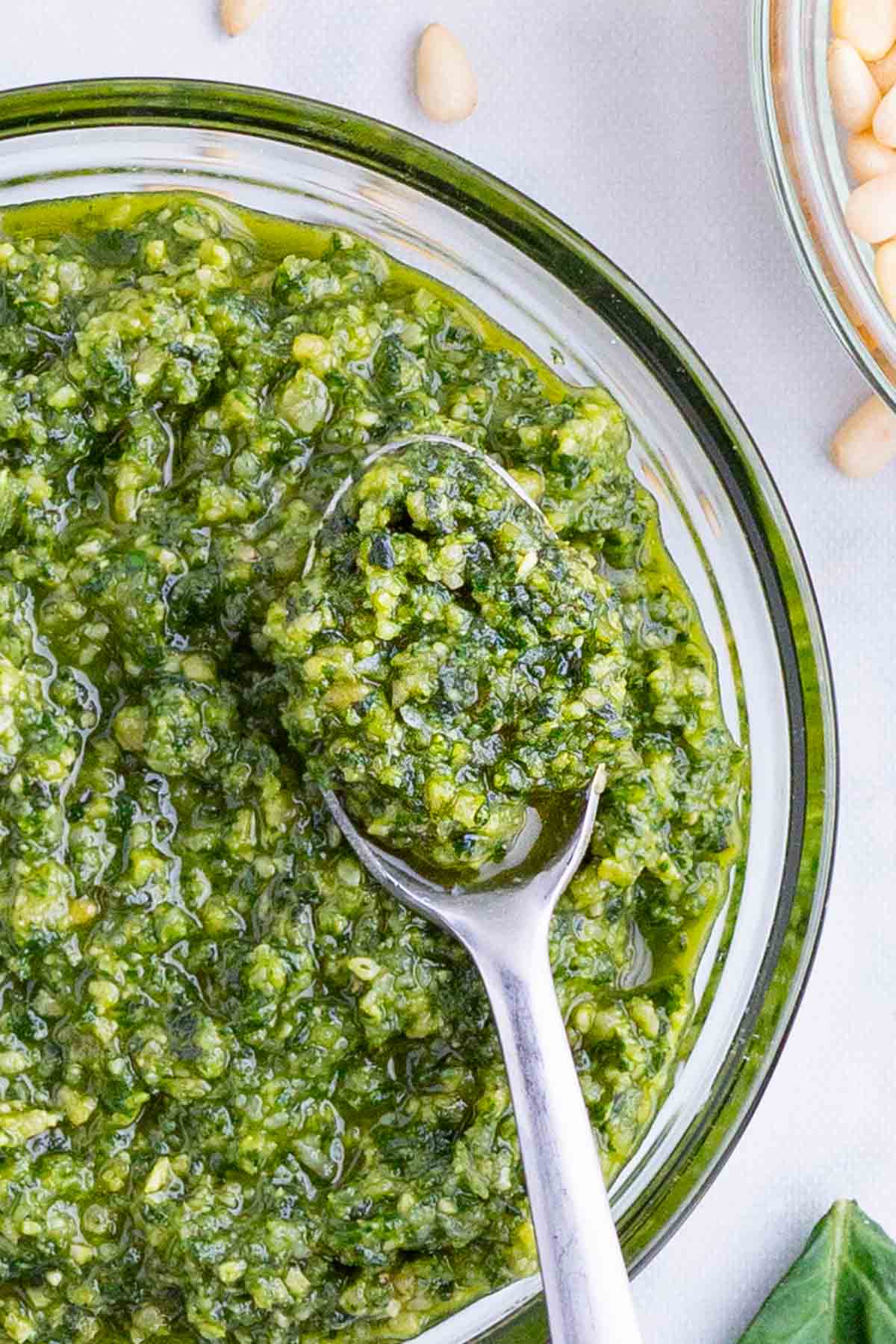 Homemade Basil Pesto Sauce RECIPE served in a clear, glass bowl and silver spoon.
