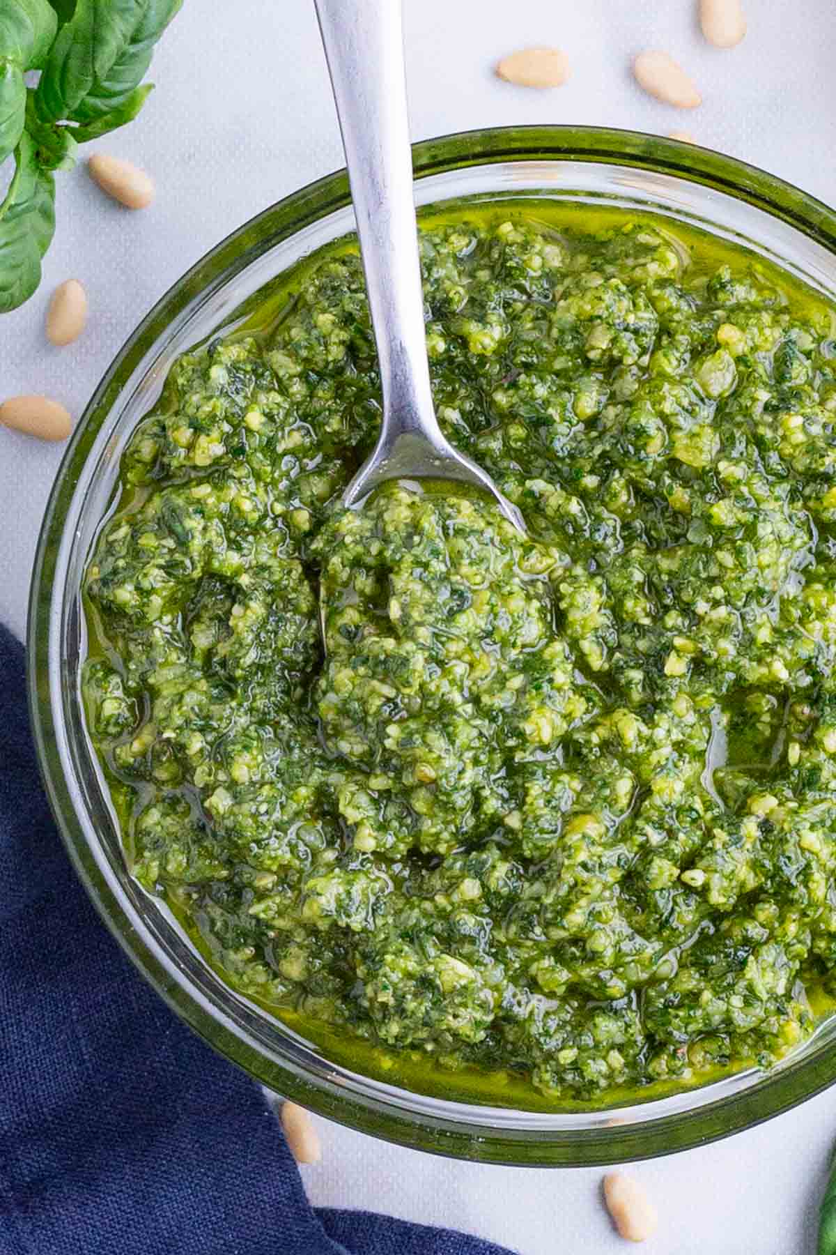 A metal spoon is lifting some healthy, fresh basil sauce.