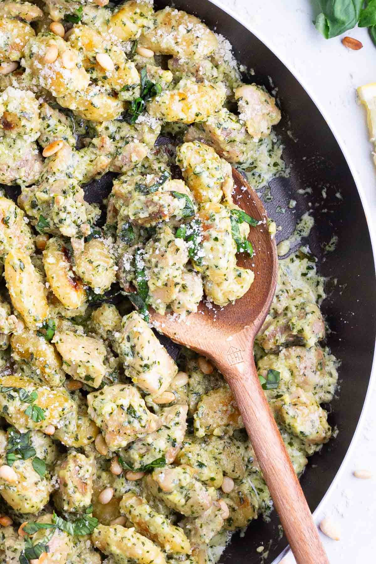 Creamy Chicken Pesto Gnocchi RECIPE served in a skillet with a wooden spoon.