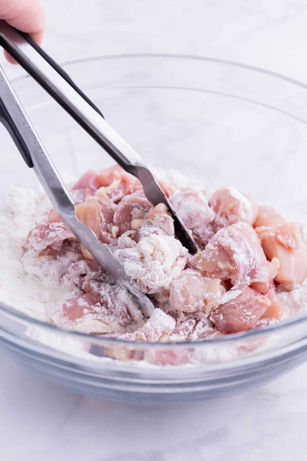 Chicken pieces are coated in a cornstarch and flour mixture.
