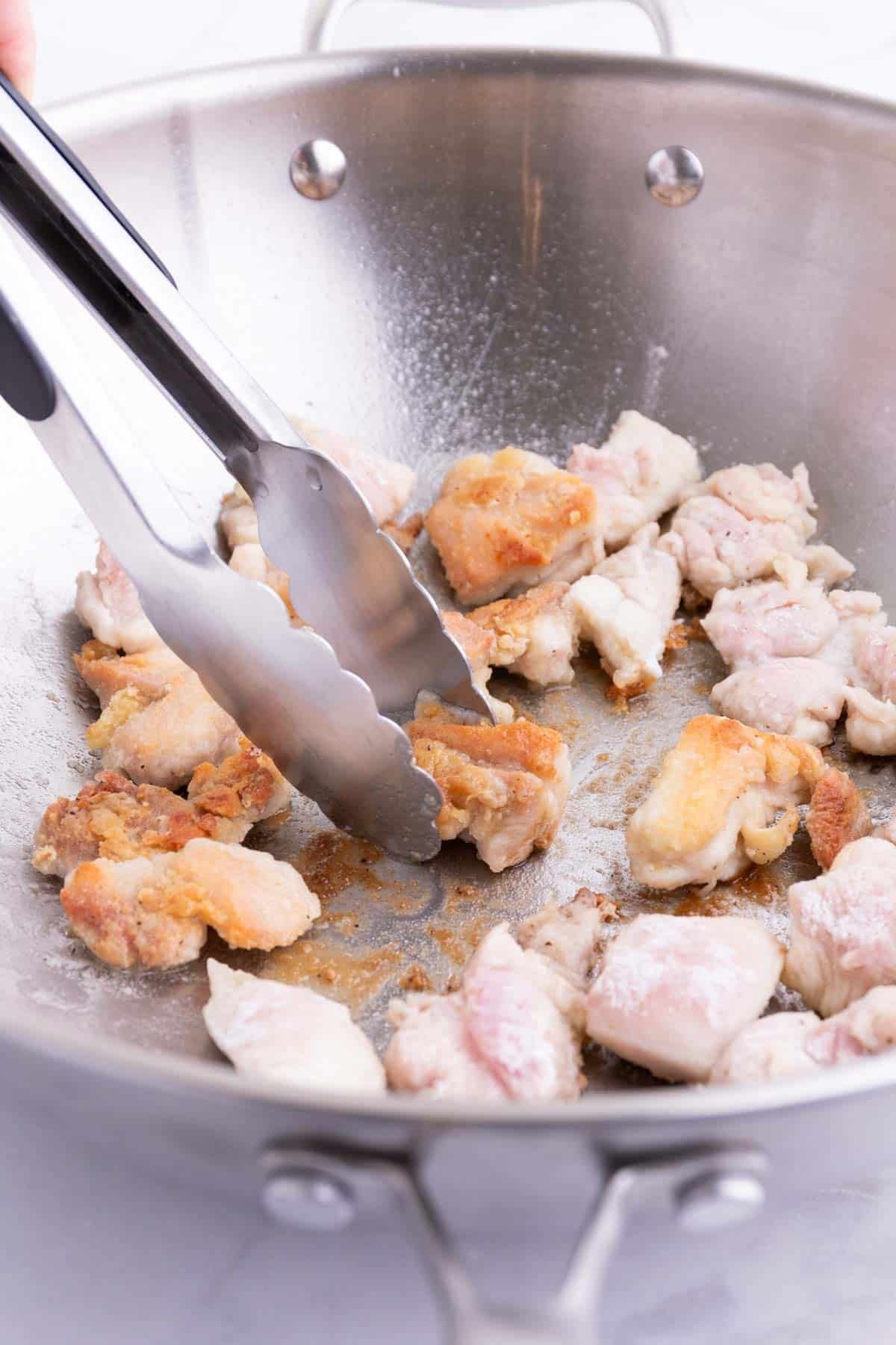 Coated chicken is lightly fried in a wok.