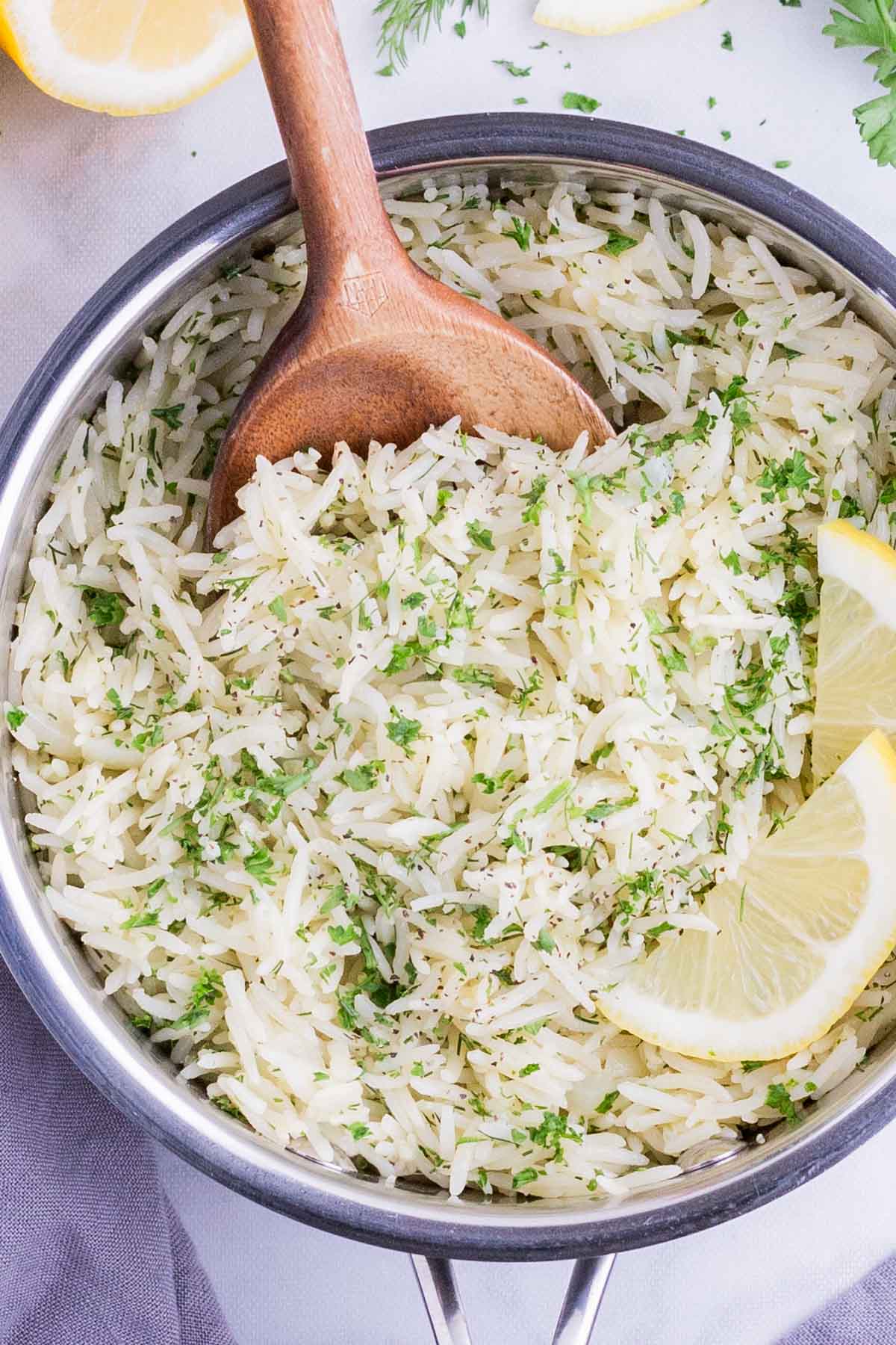 Easy Greek Lemon Rice with Fresh Herbs RECIPE in a silver bowl with a wooden spoon.