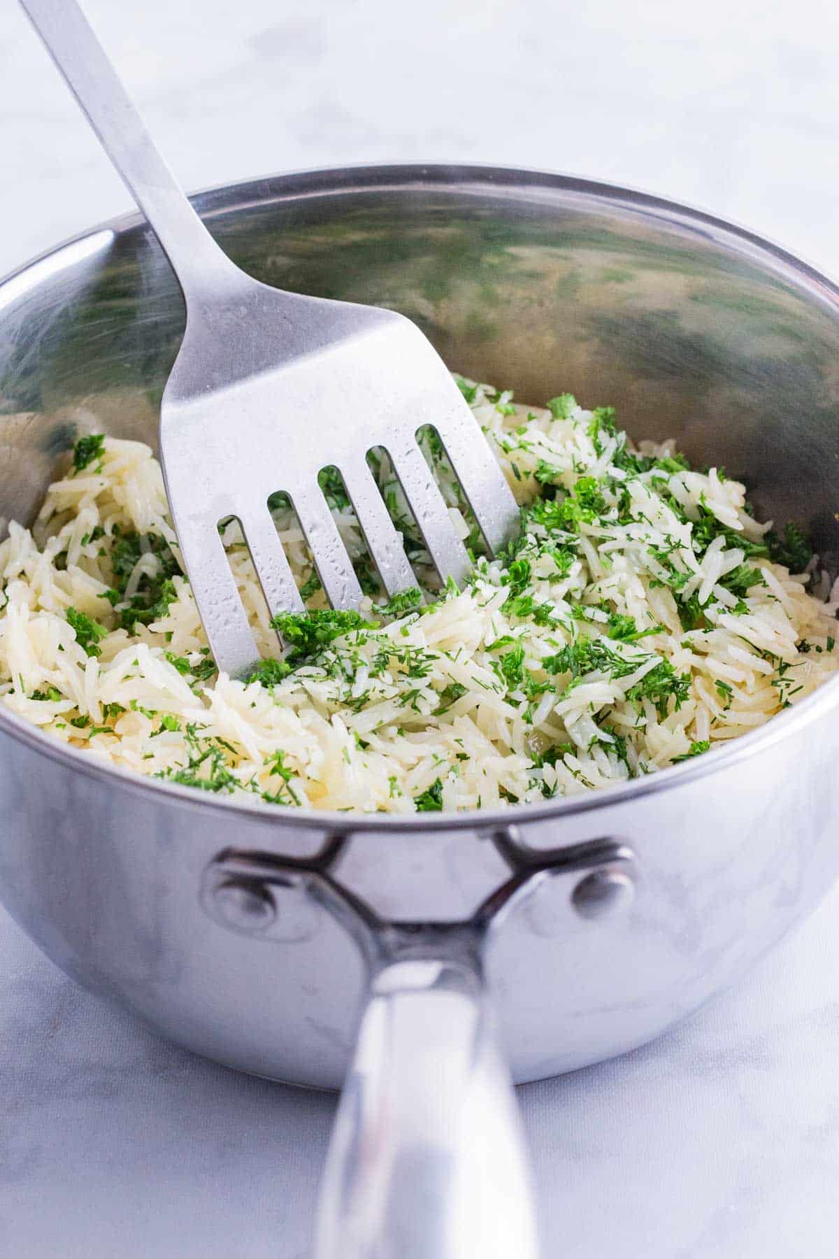A spatula fluffs up rice after cooking.