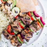 Chicken kabobs seasoned with a homemade Greek seasoning blend are served with pita and rice.