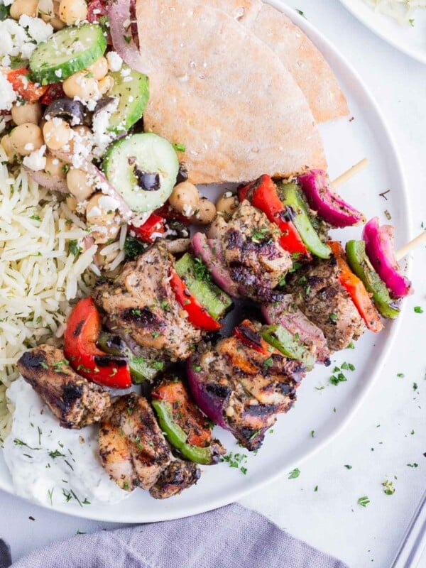 Chicken kabobs seasoned with a homemade Greek seasoning blend are served with pita and rice.