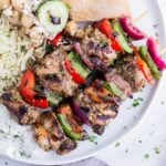 Grilled Greek chicken kabobs are served with naan and rice.