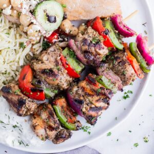 Grilled Greek chicken kabobs are served with naan and rice.