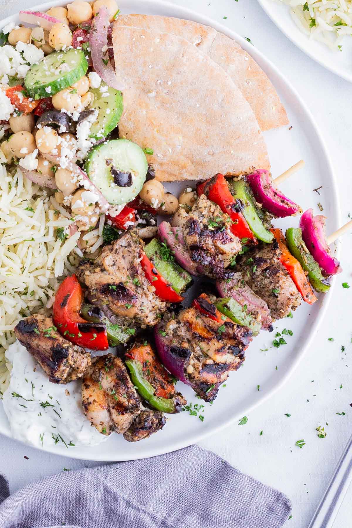 Greek chicken kabobs are served with pita and rice.