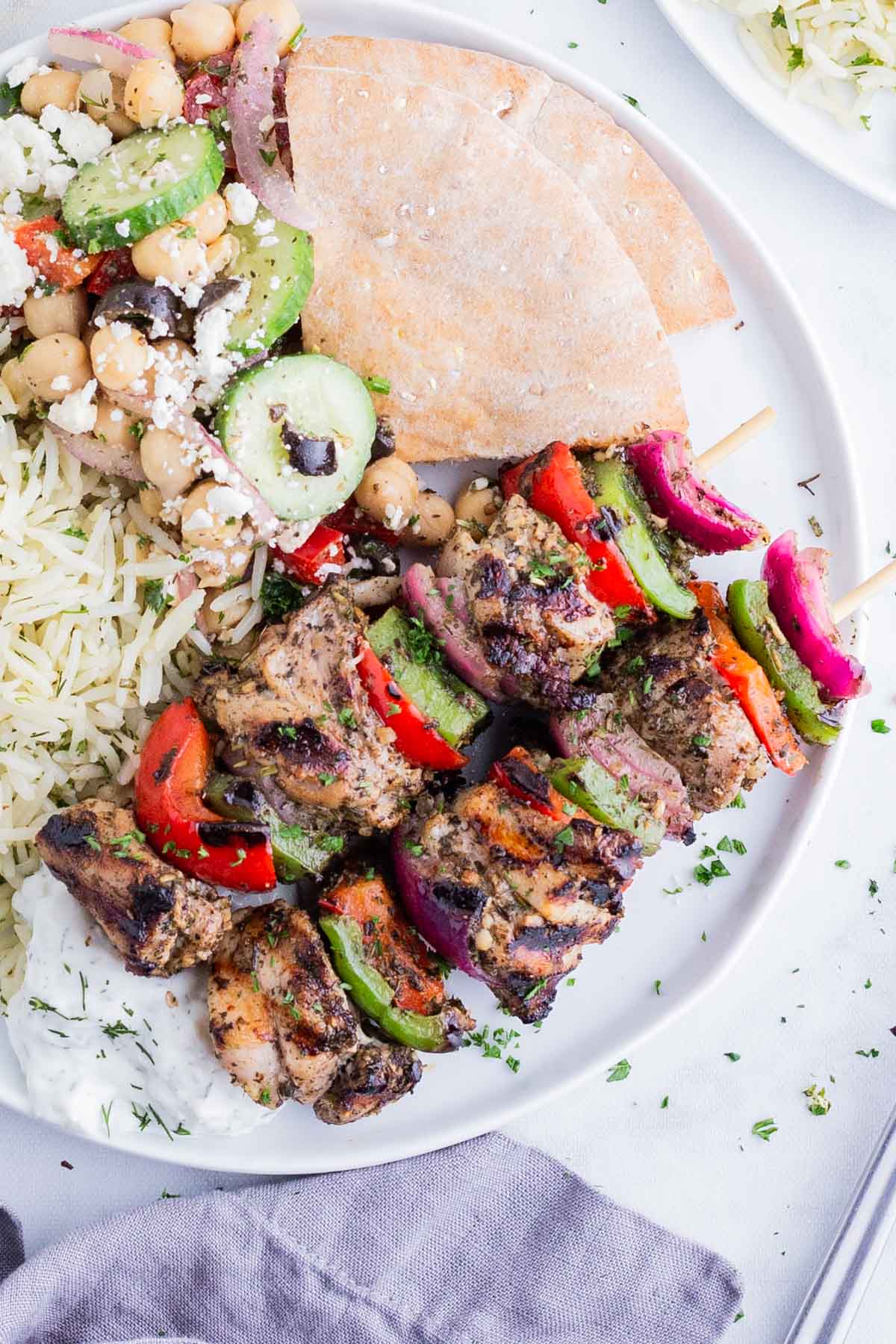 Chicken kabobs seasoned with a homemade Greek seasoning blend are served with pita and rice.