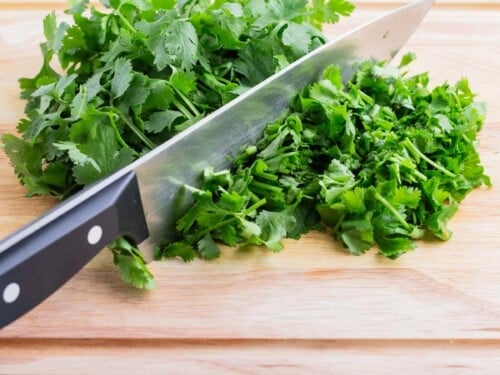 A pile of fresh cilantro is chopped on a cutting board.