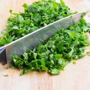 A pile of fresh cilantro is chopped on a cutting board.