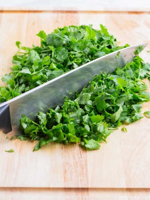 A pile of fresh cilantro is chopped on a cutting board.