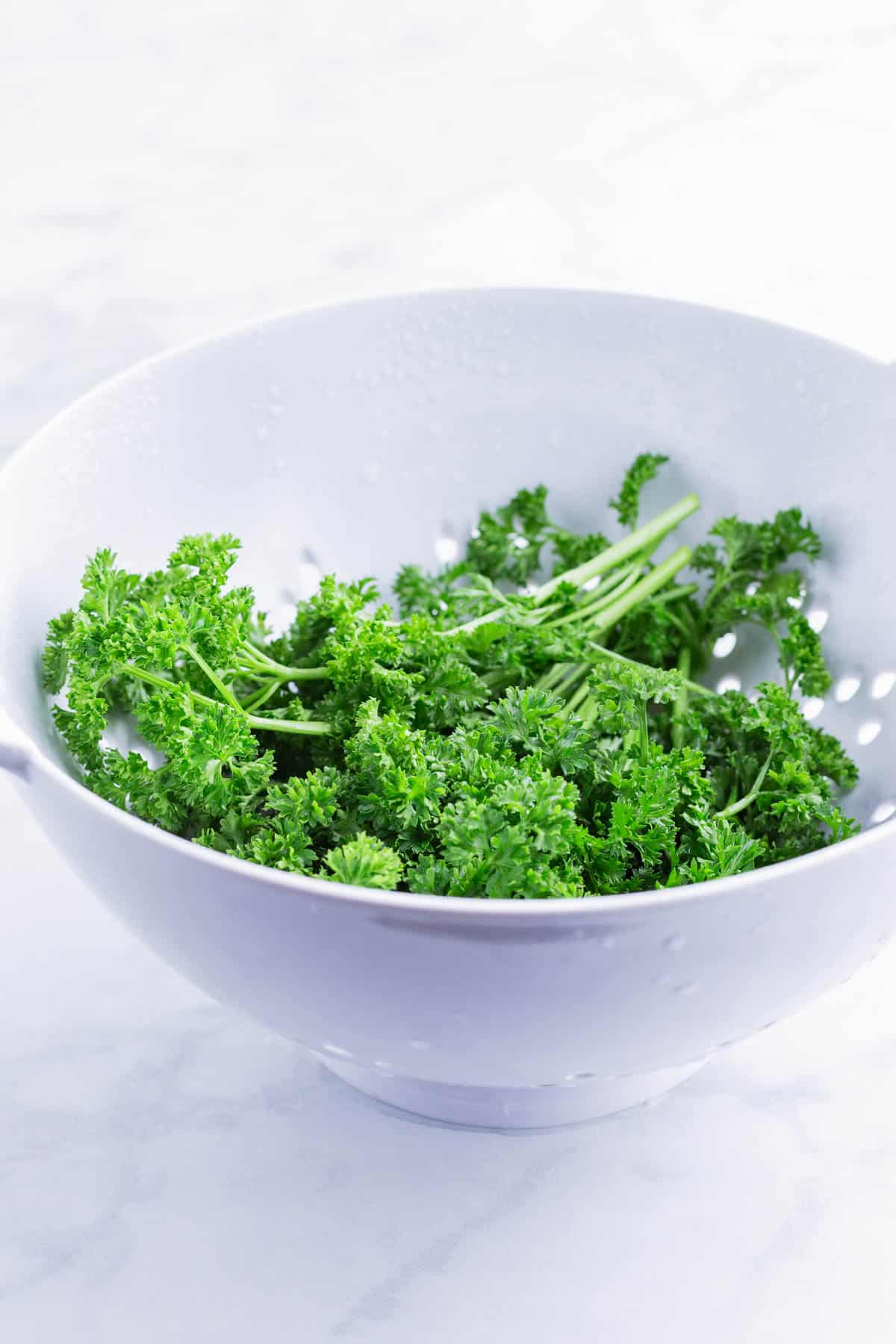 Parsley is washed in a colander.