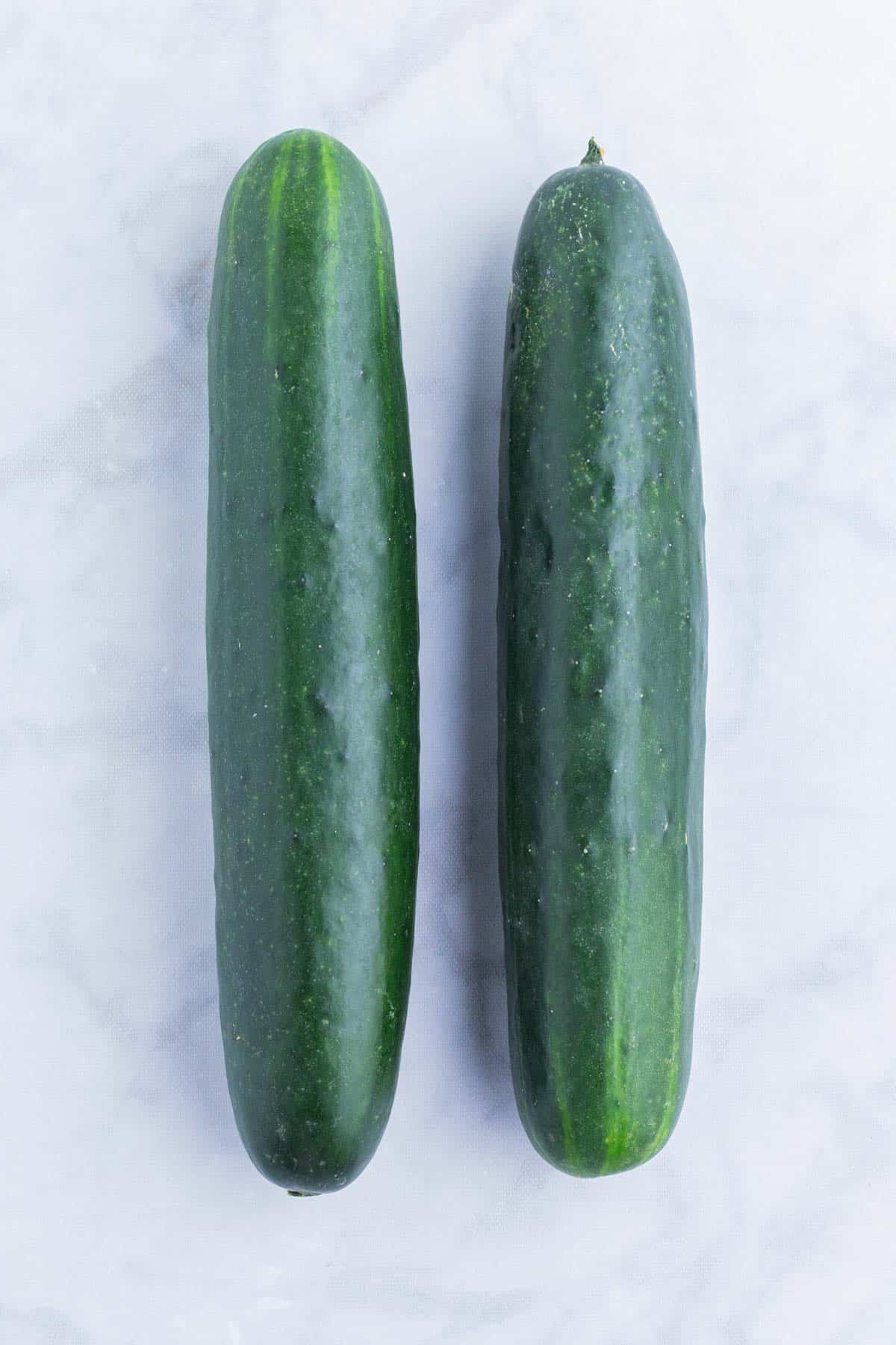 Two cucumbers are set on a counter.