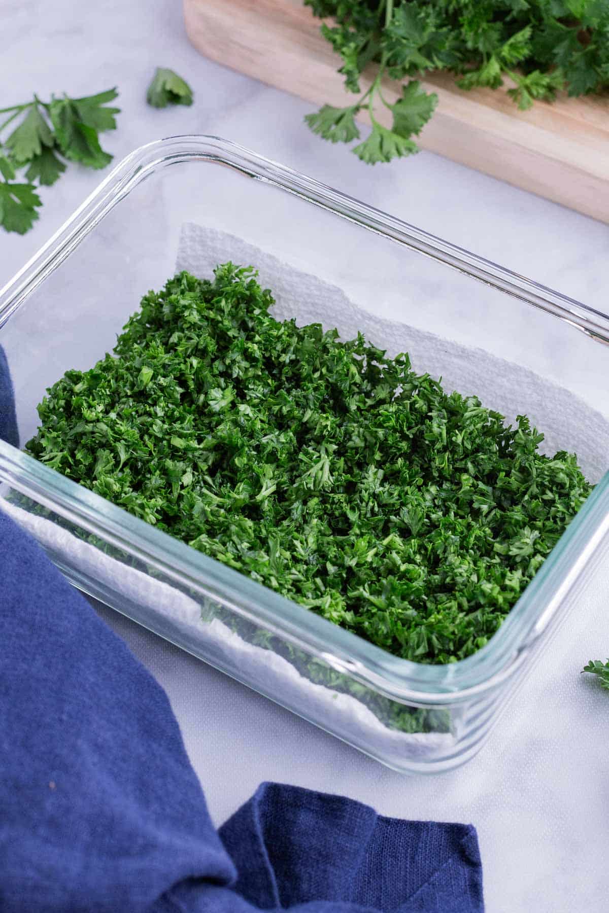 Chopped parsley is stored in a glass container.