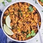 A one-pot Mexican Beef and Rice recipe is served in a white bowl for dinner with cilantro and lime wedges.