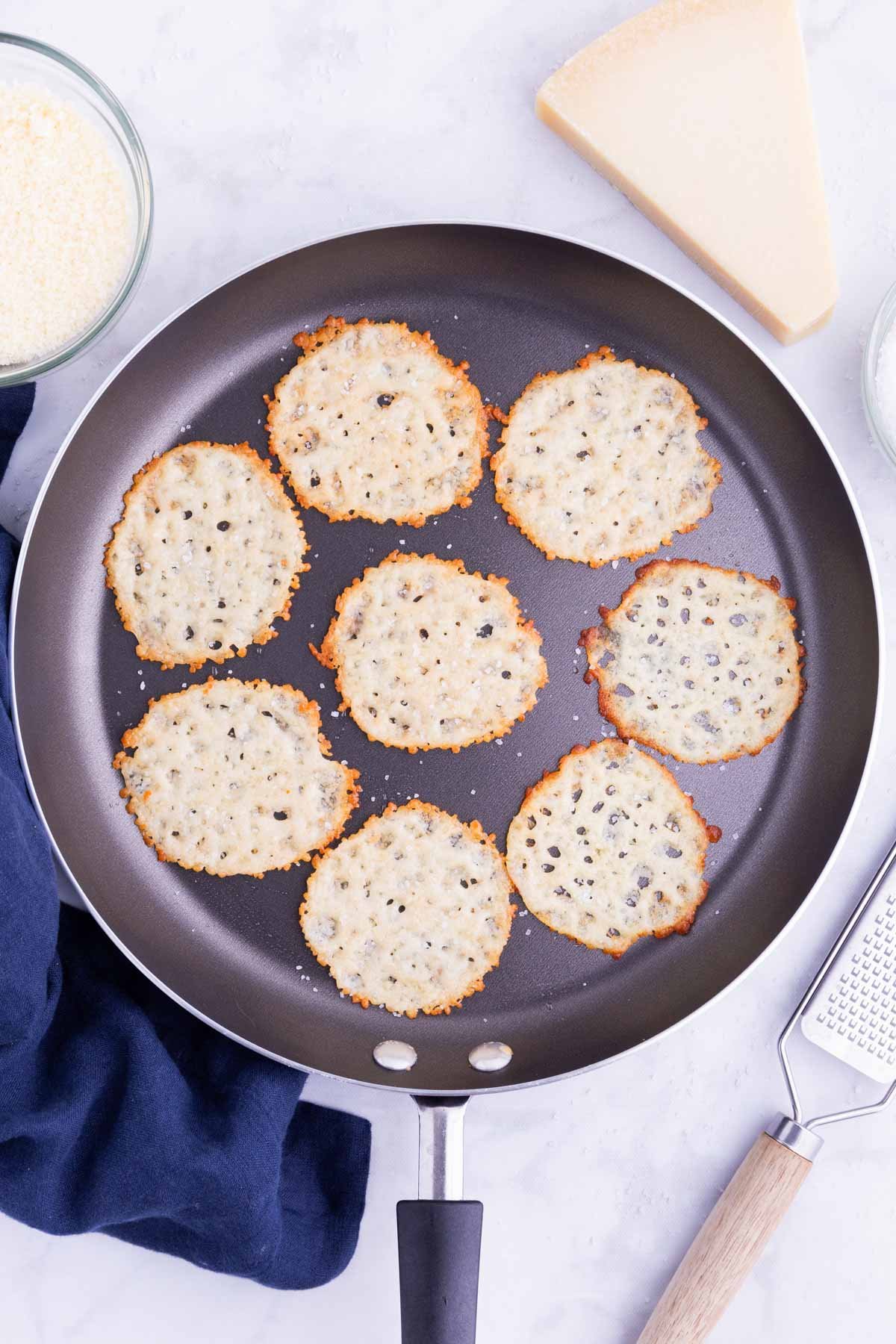 Parmesan crisps are cooked in a skillet until crispy.