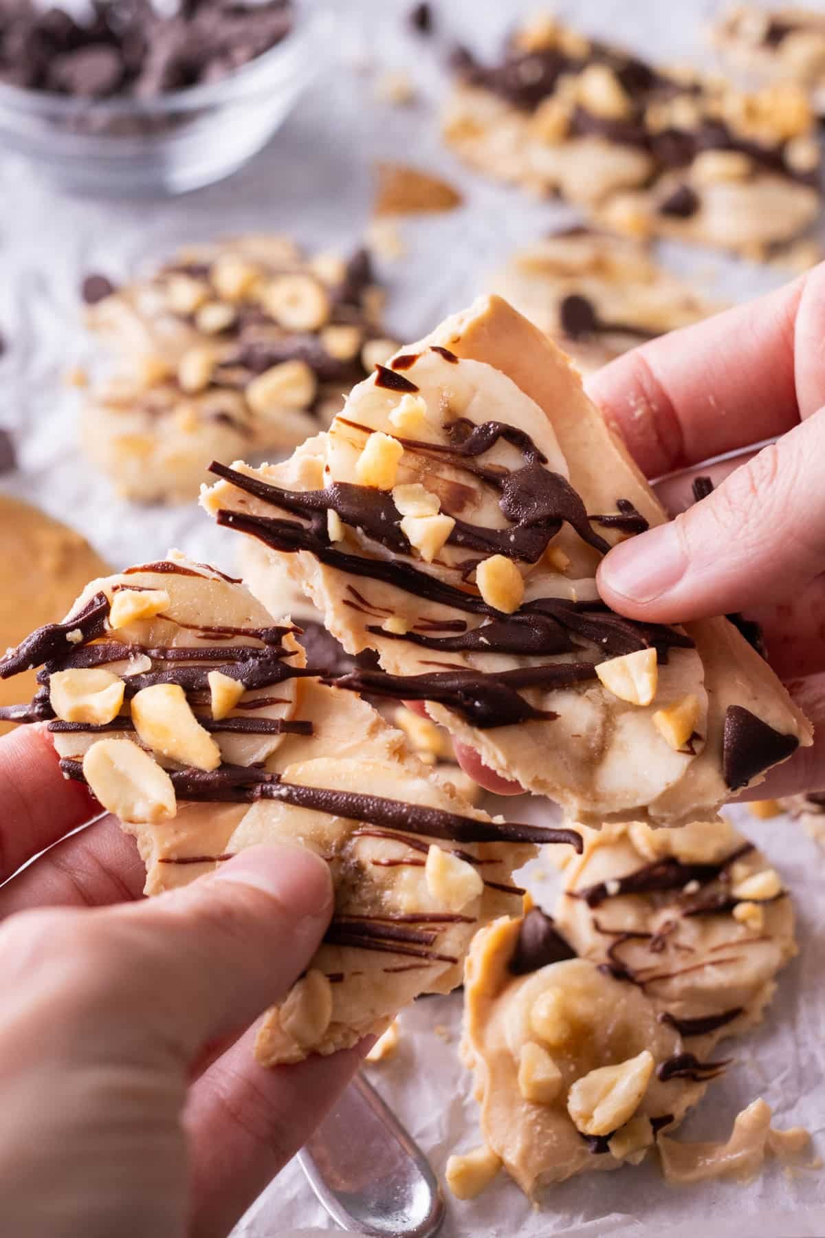 A hand breaks apart a piece of chunky monkey frozen yogurt bark.