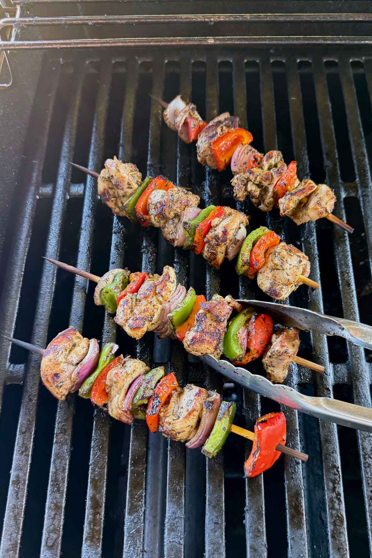 Greek Chicken Kabobs being cooked on a propane grill.
