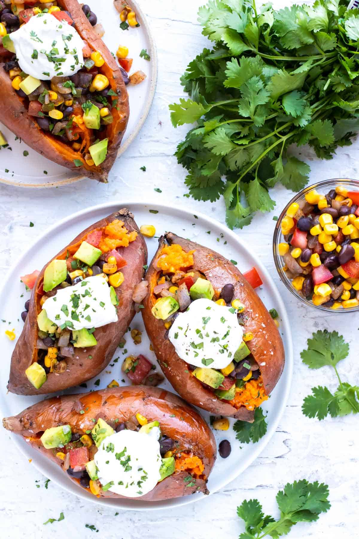 Three baked sweet potatoes stuffed with black beans, corn, and avocado.