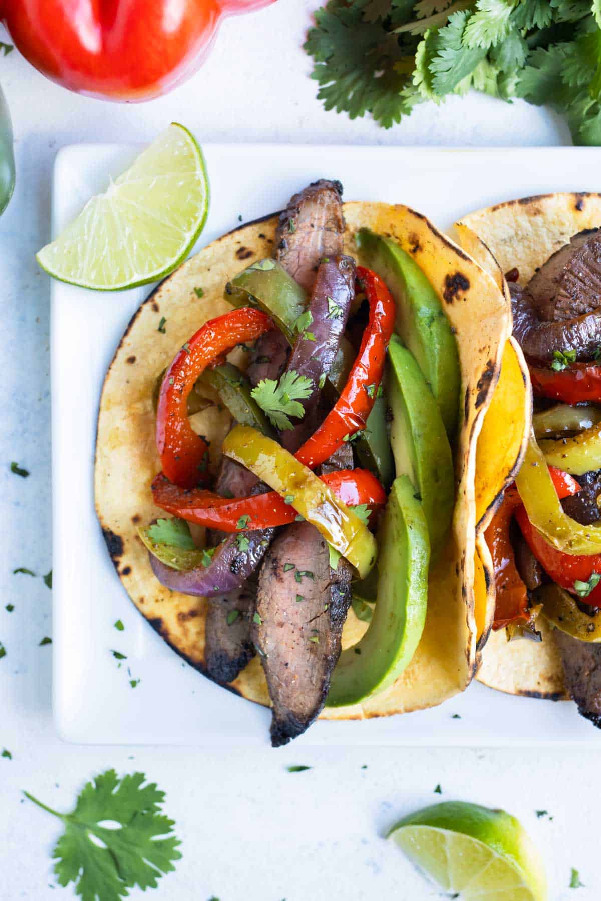 Corn tortillas are loaded with steak and vegetables.